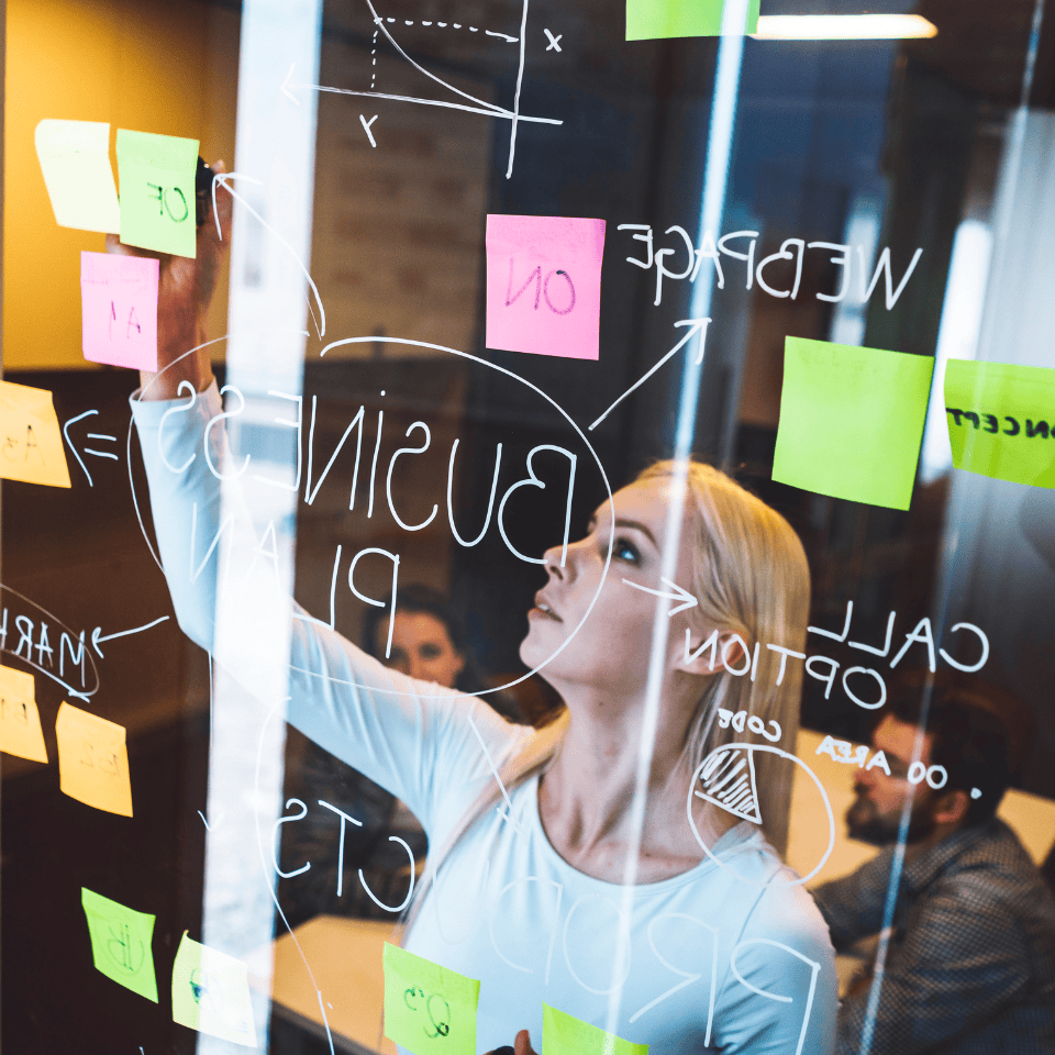 woman writing on glass wall with post its